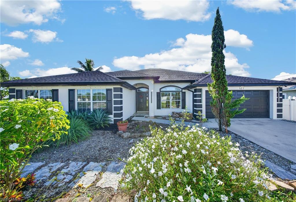 Contemporary stucco exterior with dark trim accents, a two-car garage, and an arched entry