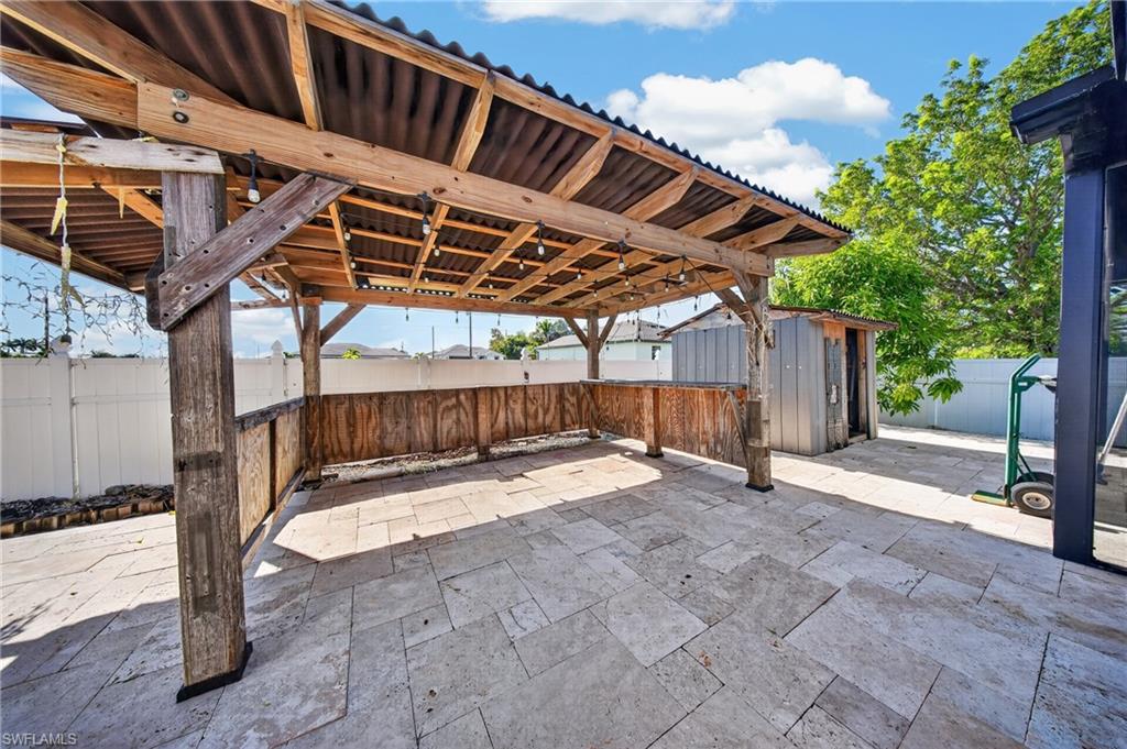 Outdoor covered patio with wood framing, corrugated roof, and tiled flooring