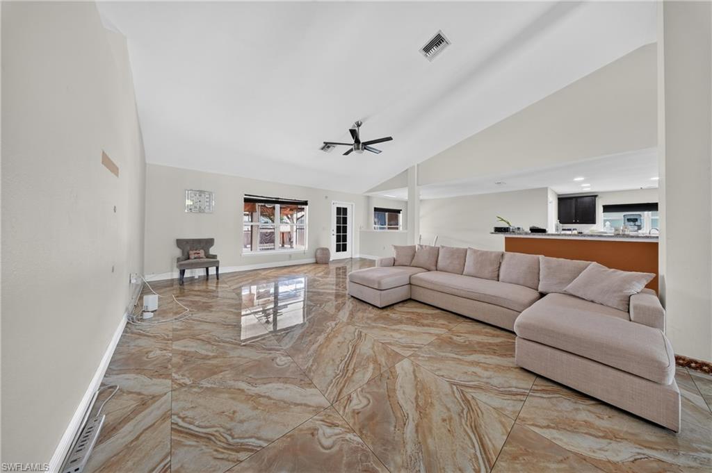 Expansive interior with vaulted ceilings, large format patterned tile flooring, and a ceiling fan