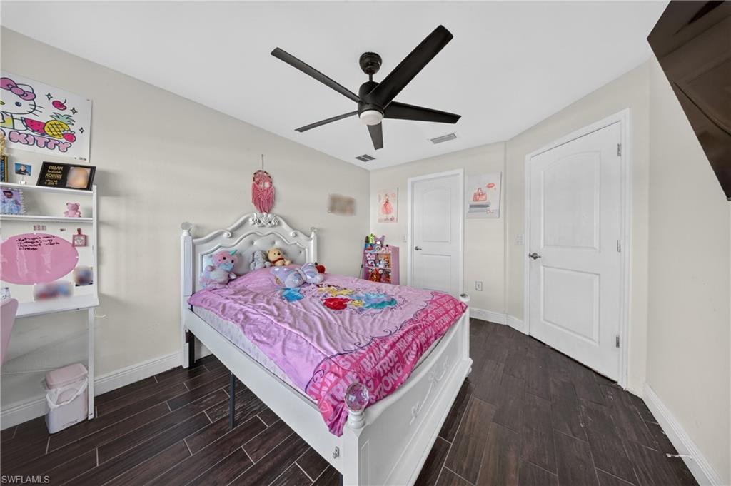Dark wood-finish flooring, white walls, and a black ceiling fan