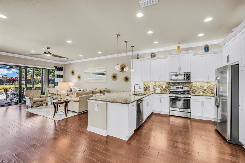 Open kitchen with granite counters, stainless steel appliances, high level cabinets with upper and under cabinet lighting, built-in pantry.