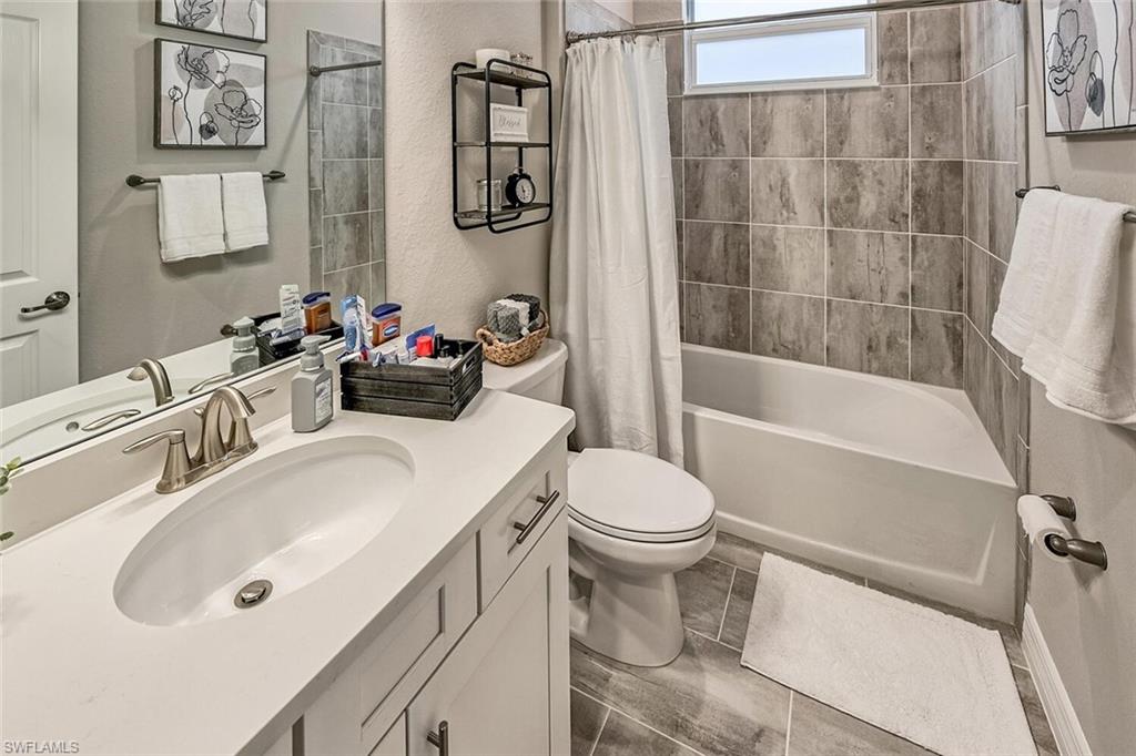 Bathroom featuring toilet, shower / bath combo with shower curtain, and vanity