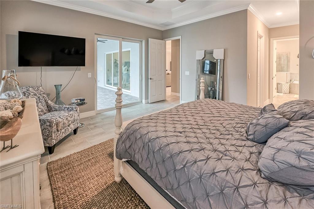Bedroom featuring a ceiling fan, baseboards, access to exterior, ensuite bath, and crown molding