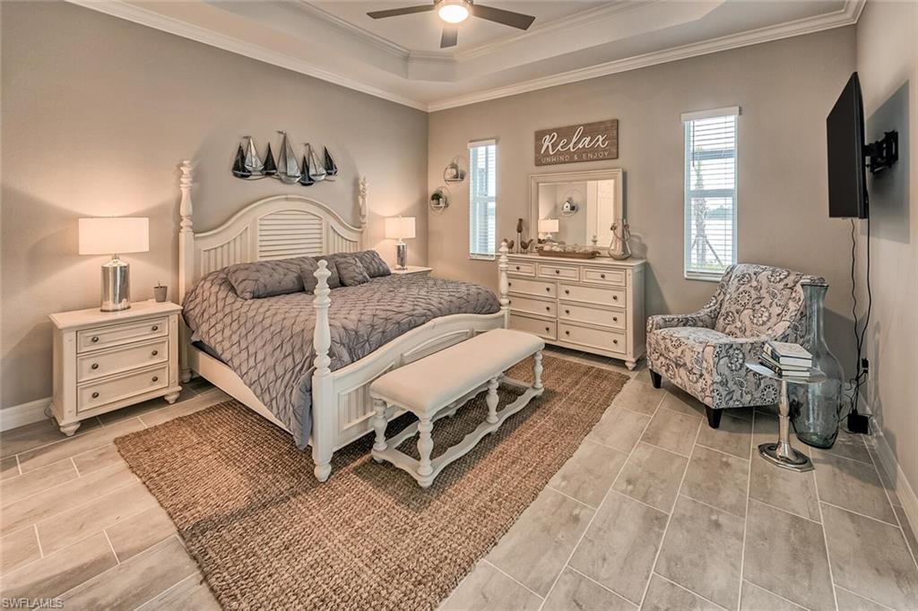 Bedroom featuring ornamental molding, a tray ceiling, and baseboards