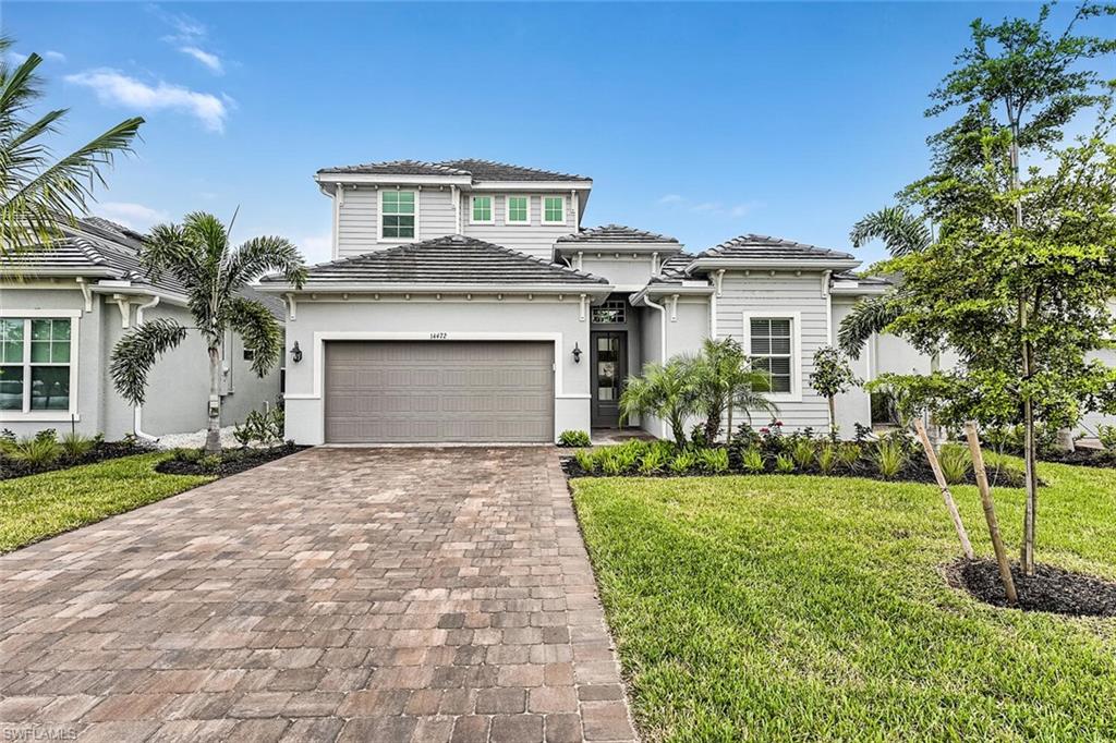 Prairie-style home featuring stucco siding, a tiled roof, decorative driveway, and a front yard