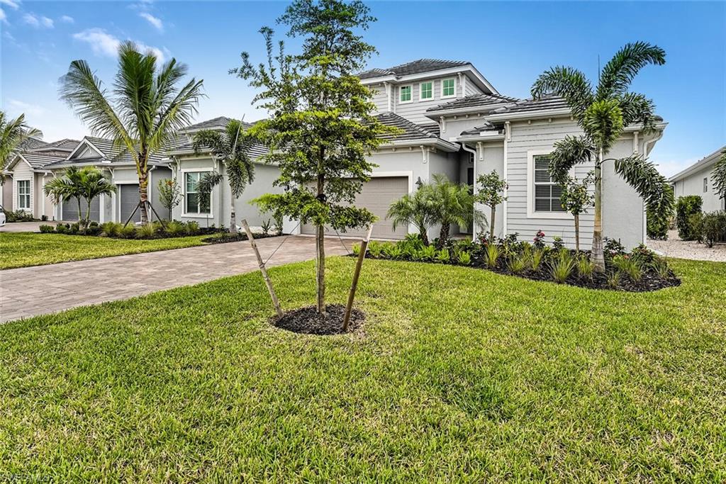 View of front of property featuring a garage, a front lawn, decorative driveway, and stucco siding