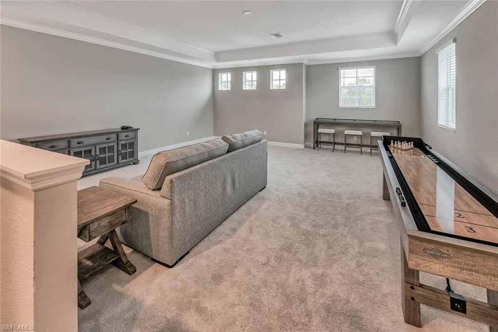Carpeted living room with ornamental molding, a tray ceiling, and baseboards