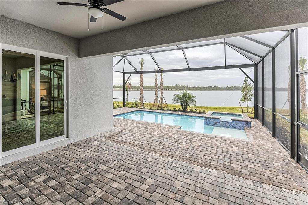 View of swimming pool with a ceiling fan, a patio area, a water view, and a pool with connected hot tub