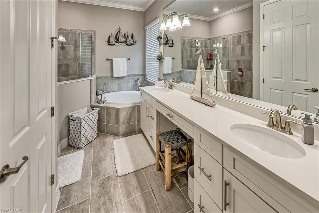 Bathroom featuring a garden tub, crown molding, a walk in shower, and a sink