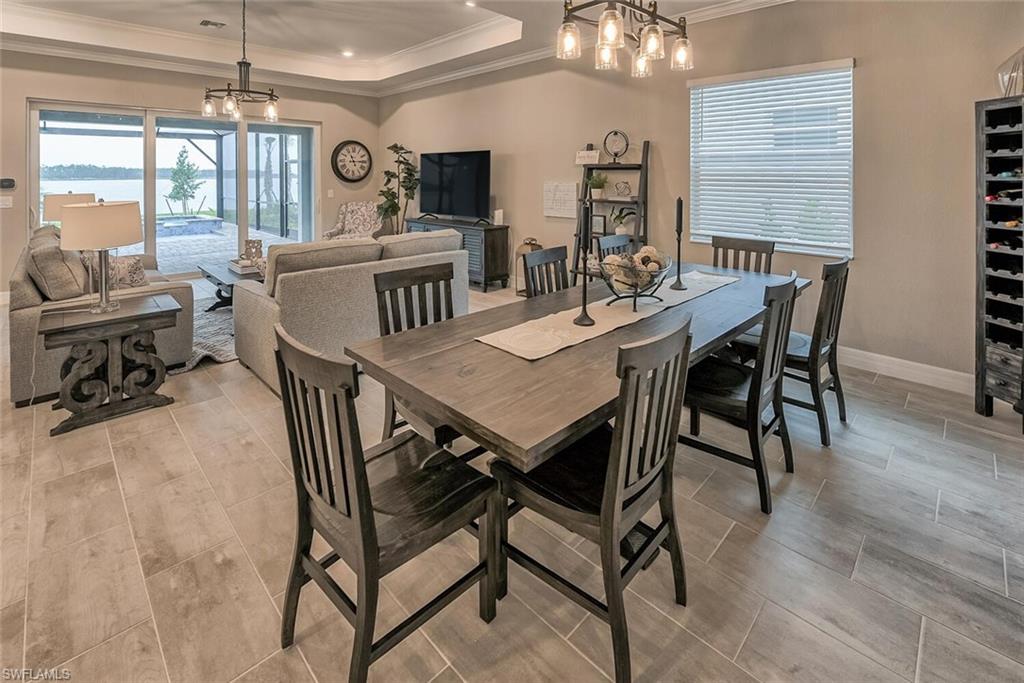 Dining room with baseboards, crown molding, a raised ceiling, and an inviting chandelier