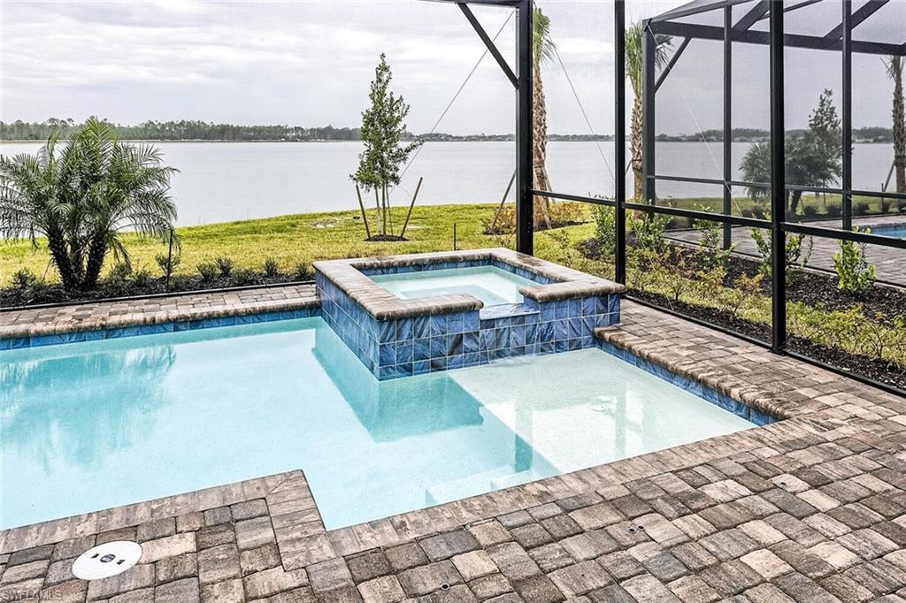 View of swimming pool featuring a water view, a pool with connected hot tub, and a lanai
