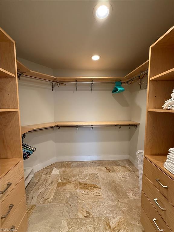 Recessed lighting, wood-finish shelving, built-in drawer storage, and stone tile flooring