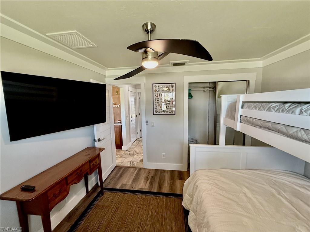 Built-in bunk beds, modern ceiling fan with integrated lighting, wood-finish flooring, sliding closet doors, and crown molding