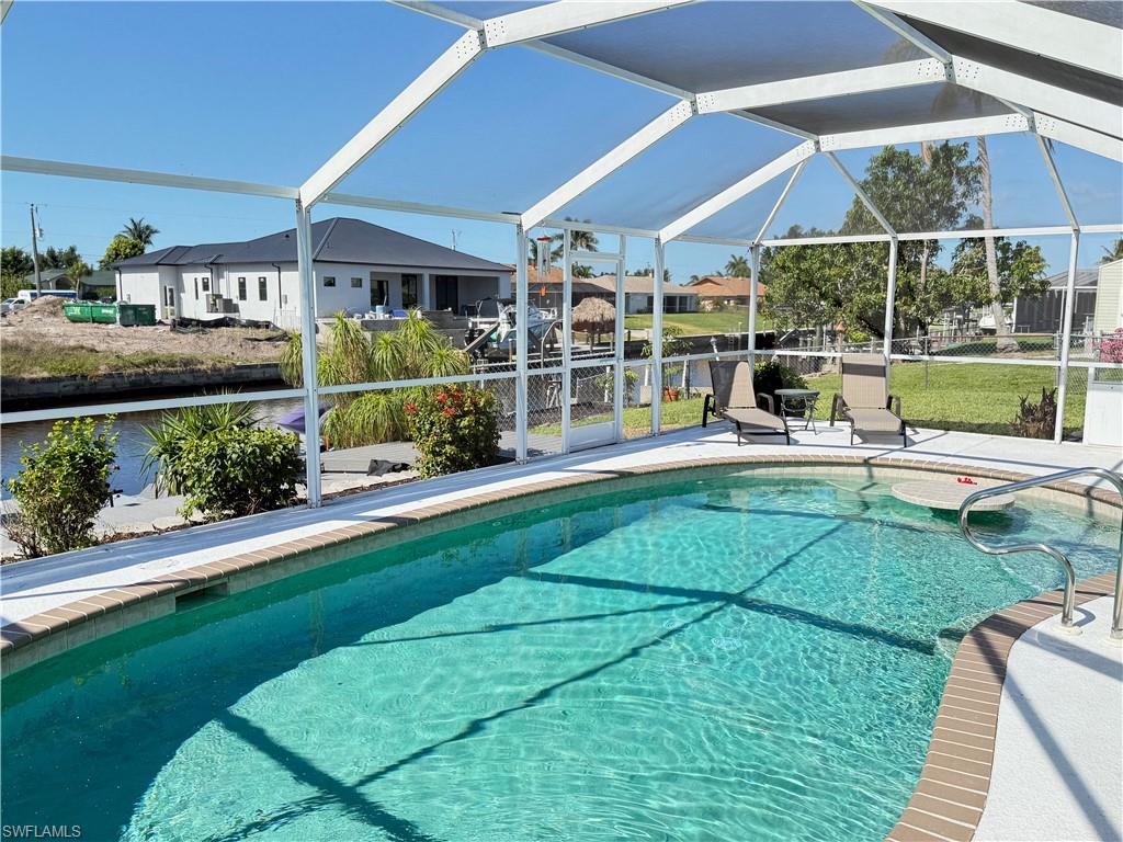 Screened enclosure with an in-ground swimming pool, integrated in-pool seating, and stainless steel grab rails