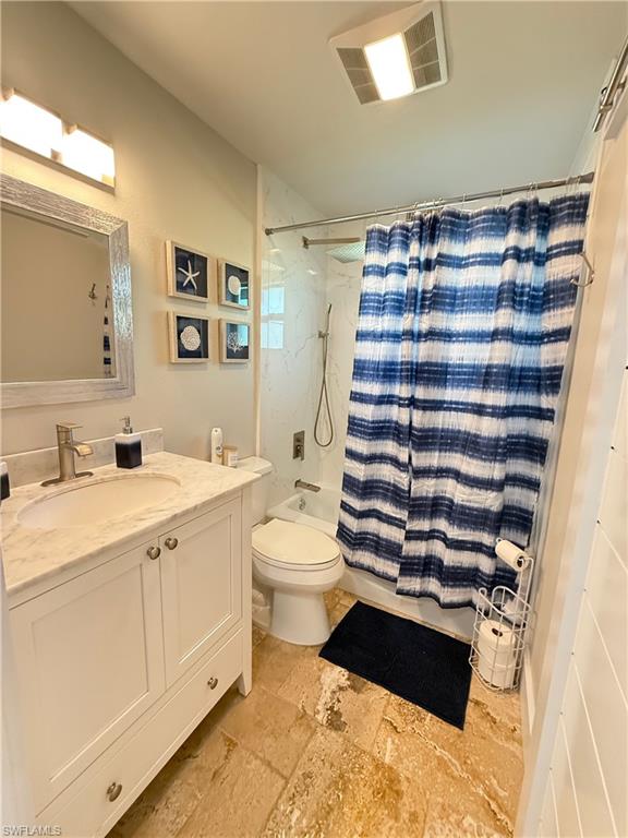 White vanity with a single basin, stone countertop, and brushed nickel faucet
