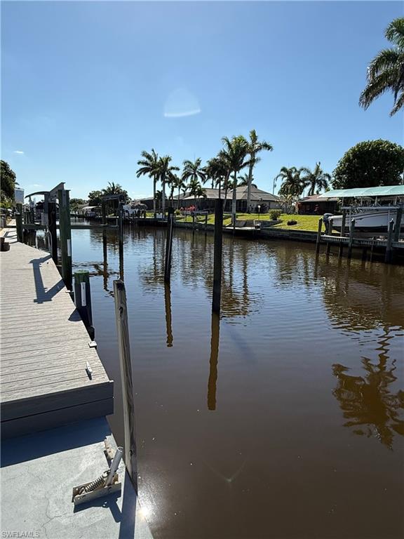 Canal-front property featuring a private dock, mature palm trees, and waterfront access