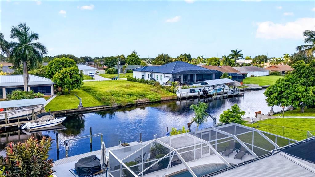 Waterfront property with canal access, screened pool enclosure, boat dock, and mature palm trees