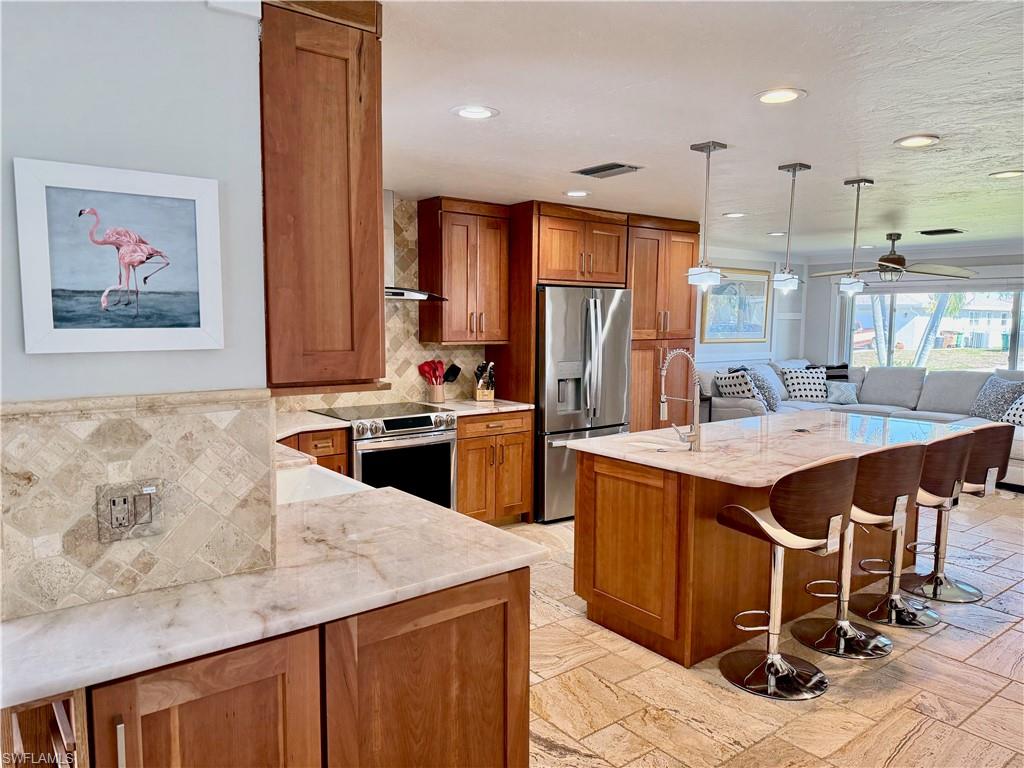 Kitchen featuring wood cabinetry, stainless steel appliances, a center island with countertop seating, recessed lighting, and tile flooring