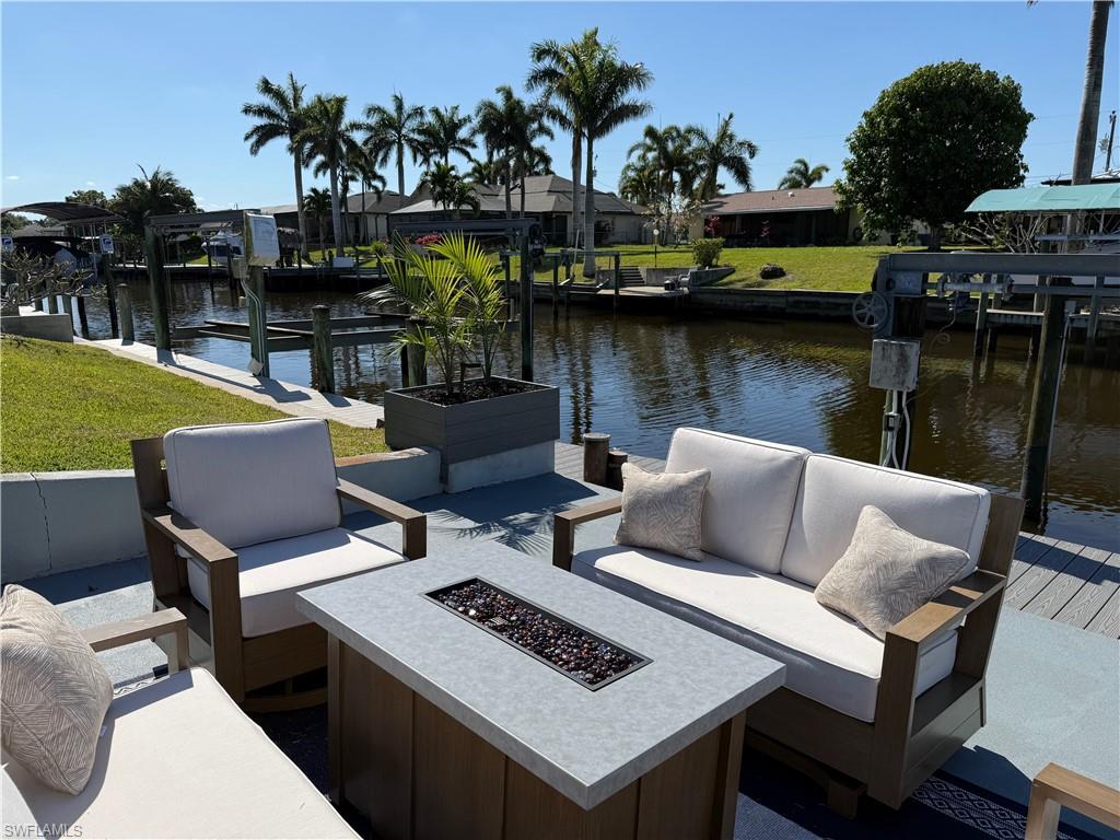 Waterfront property featuring a concrete seawall, boat dock, and lush green lawn