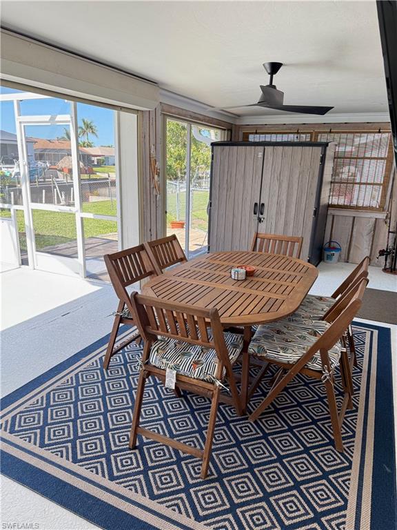 Screened enclosure with sliding glass doors, a ceiling fan, and a built-in storage cabinet