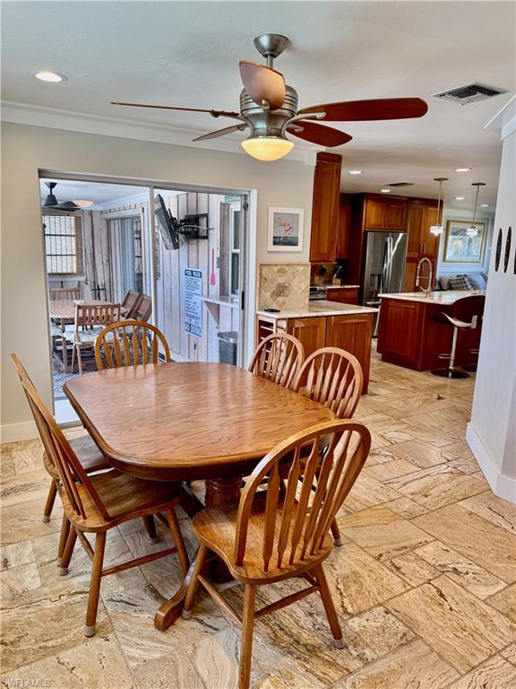Stone tile flooring, recessed lighting, ceiling fan with integrated lighting, wood cabinetry, and sliding glass doors
