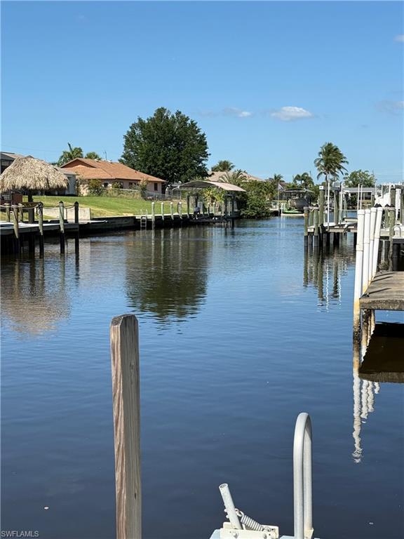 Waterfront property featuring multiple boat docks, a covered boat lift, and a thatched tiki hut