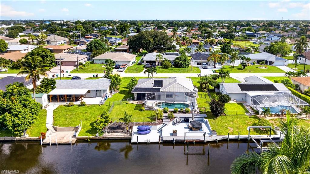 Waterfront property featuring a private boat dock, spacious backyard, and a screened swimming pool with an integrated spa