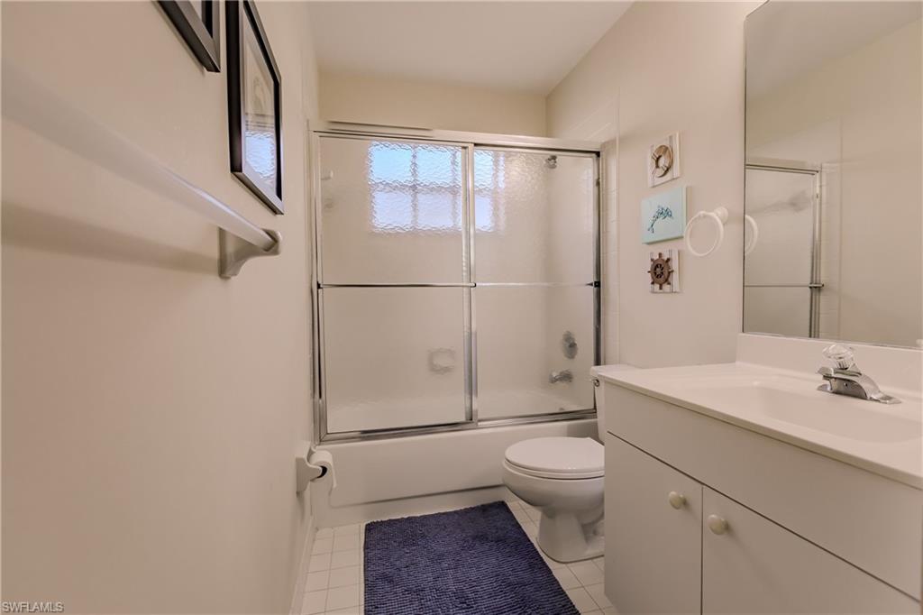 Full bathroom featuring vanity, toilet, shower / bath combination with glass door, and tile patterned flooring