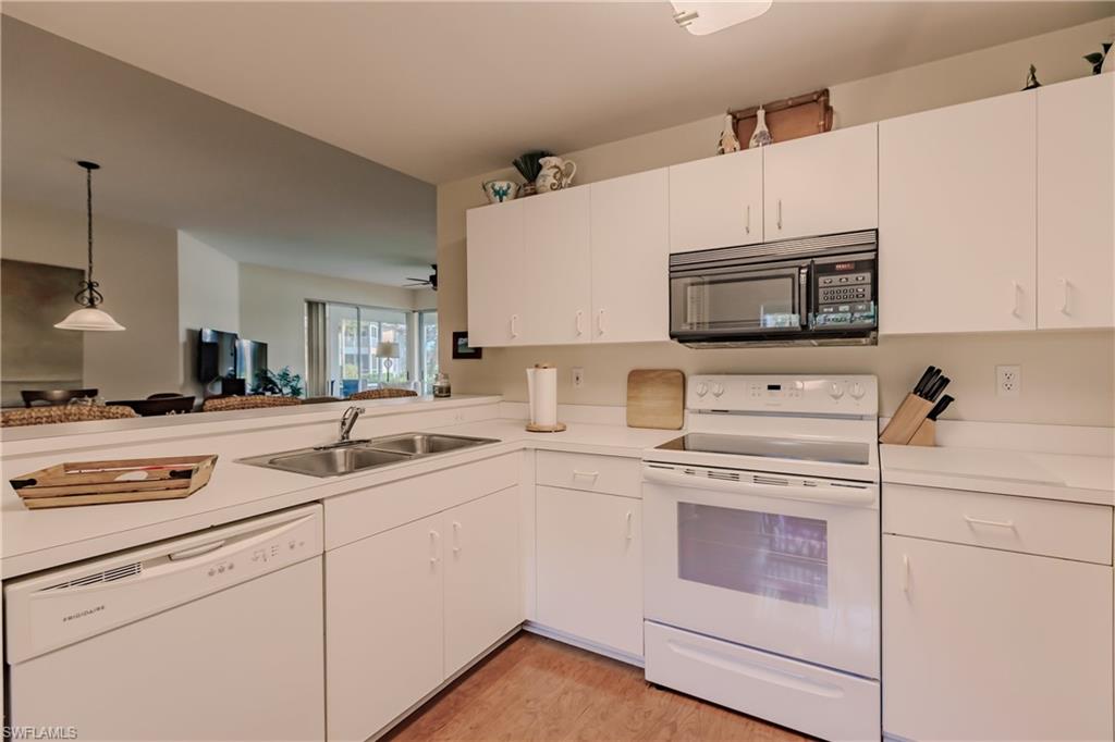 Kitchen featuring white cabinets, light hardwood / wood-style floors, decorative light fixtures, sink, and white appliances