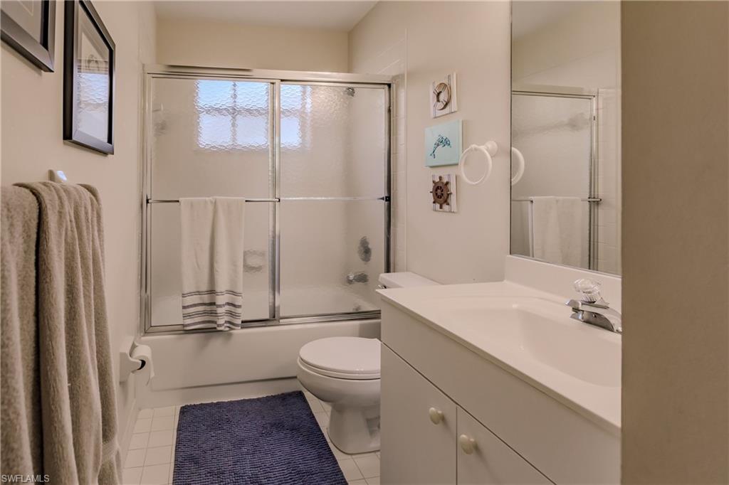 Full bathroom featuring vanity, toilet, combined bath / shower with glass door, and tile patterned flooring