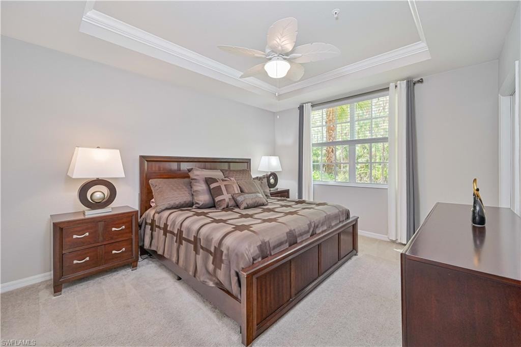 Spacious guest bedroom featuring a tray ceiling, plush carpeting, abundant natural light, and peaceful views of the lush tropical landscape.