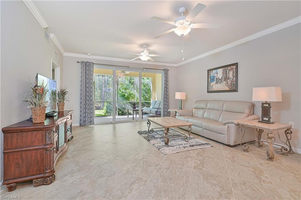 Bright and spacious great room featuring elegant tile flooring, crown molding, soaring ceilings, and expansive sliding glass doors that open to a private screened lanai with tranquil preserve views.