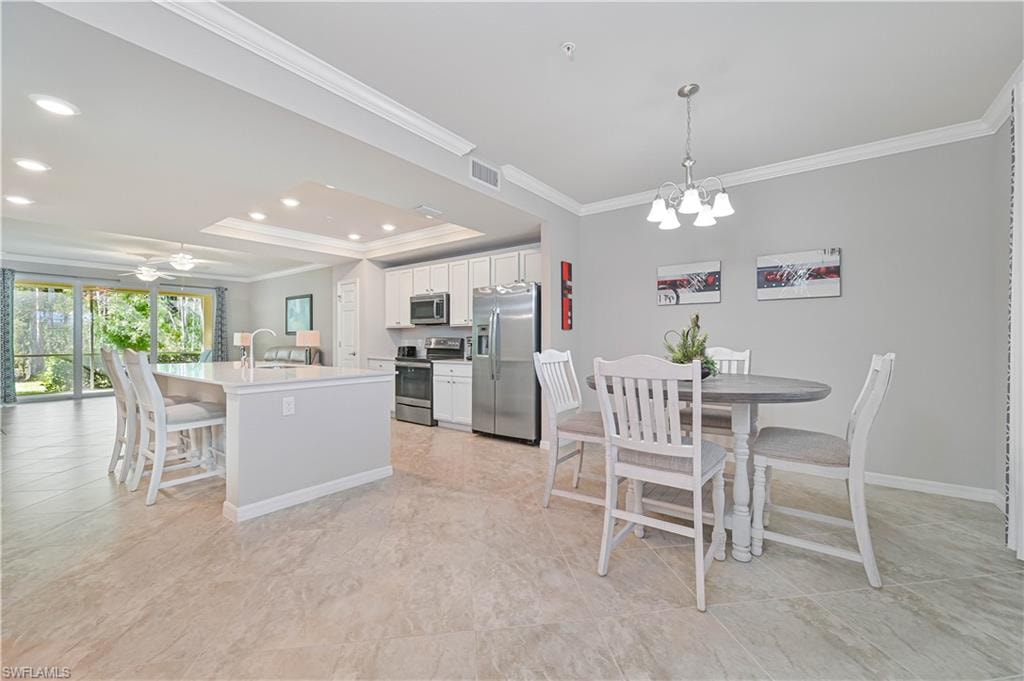 The open-concept kitchen and dining area feature a large center island with seating, stainless steel appliances, crown molding, and seamless flow into the spacious great room—perfect for entertaining.