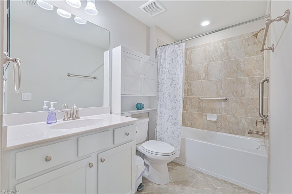 Stylish guest bathroom featuring a spacious vanity, tile flooring, a tiled tub/shower combination, and built-in linen storage for added convenience.