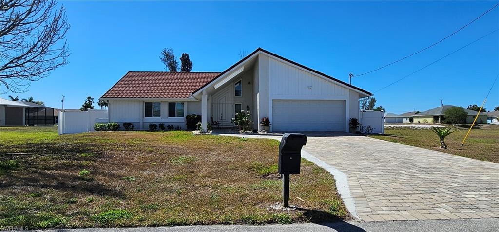 View of front of house with a tiled roof, decorative driveway, and a garage