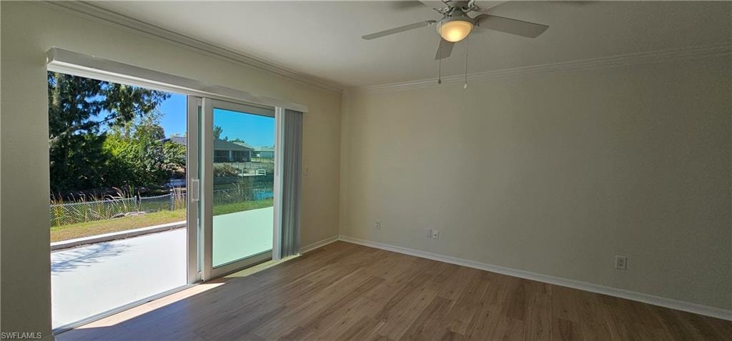 Empty room with wood finished floors, ceiling fan, and ornamental molding