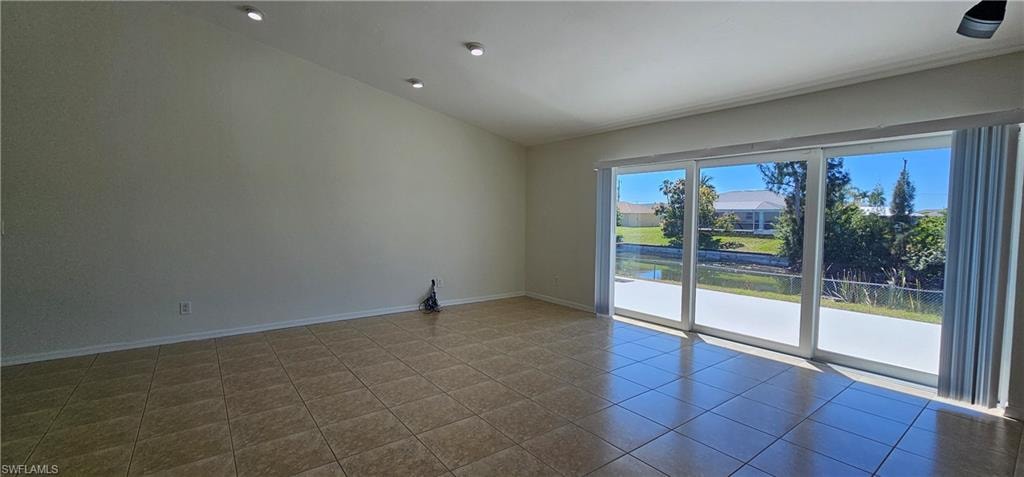 Tiled spare room featuring lofted ceiling and a water view