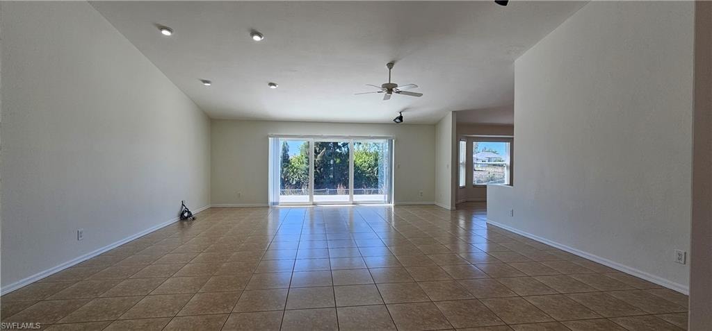 Unfurnished room with a ceiling fan, vaulted ceiling, and light tile patterned floors