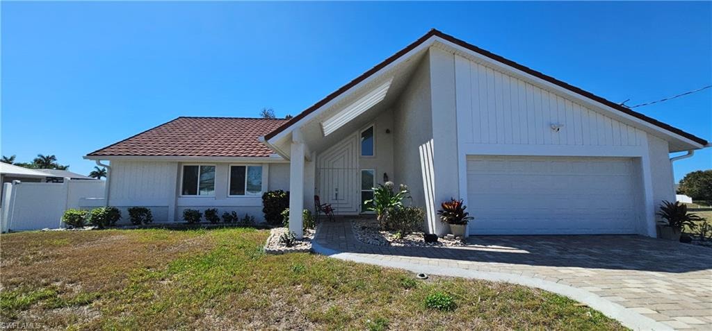 View of front of house featuring a garage, driveway, and a tile roof