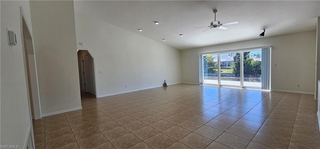 Empty room featuring ceiling fan, tile patterned floors, and lofted ceiling