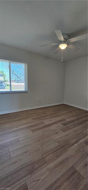 Unfurnished room featuring a ceiling fan and dark wood-style flooring