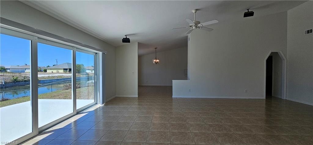 Spare room featuring ceiling fan, a water view, vaulted ceiling, and arched walkways