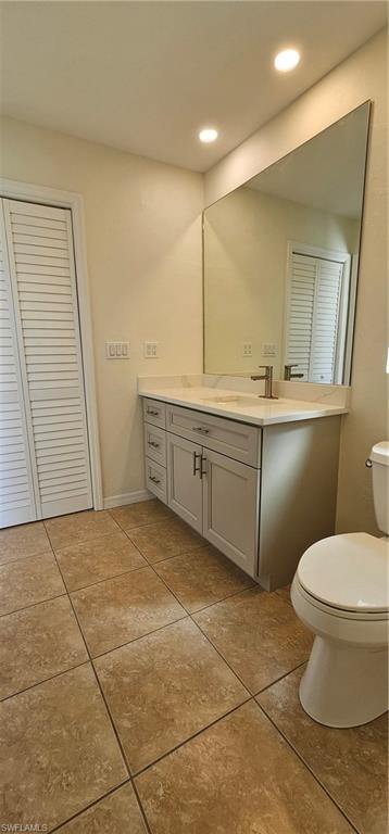 Bathroom featuring a closet, vanity, light tile patterned floors, and recessed lighting