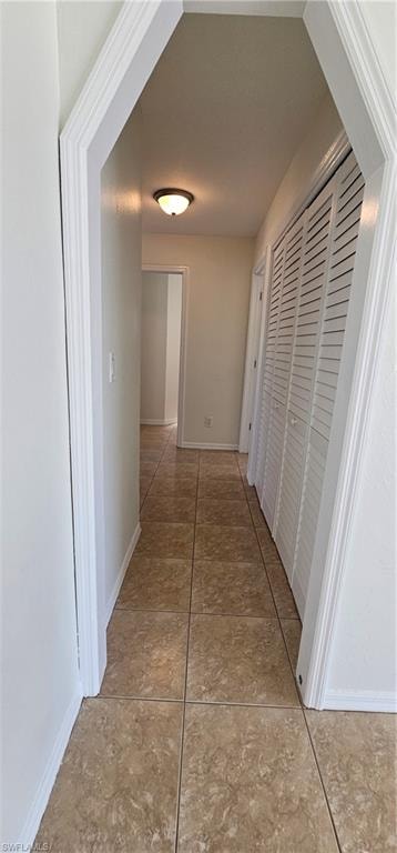Corridor featuring baseboards and light tile patterned floors