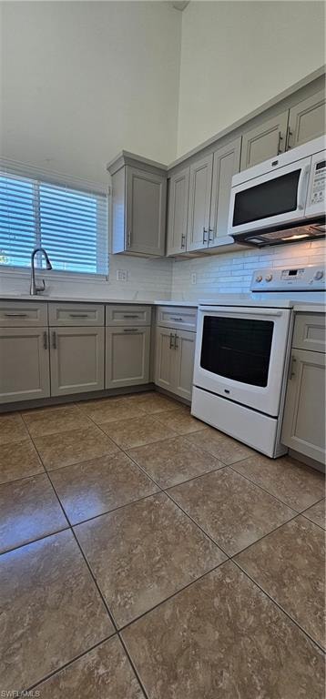 Kitchen featuring gray cabinets, range, backsplash, and light countertops