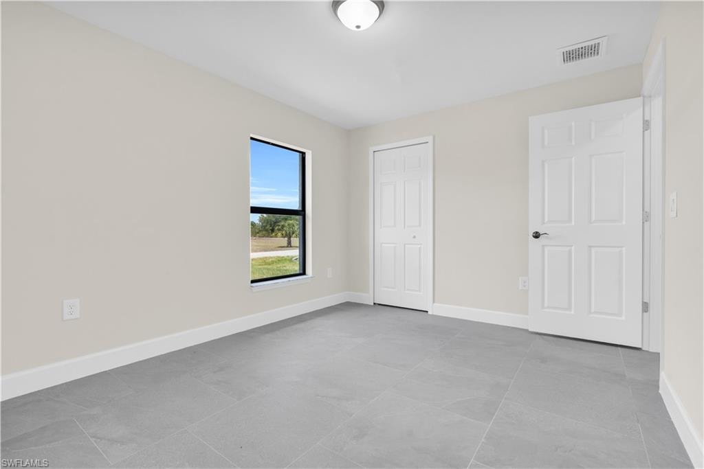 Recessed ceiling light, grey tile flooring, white trim, white paneled door, and a white bi-fold closet door