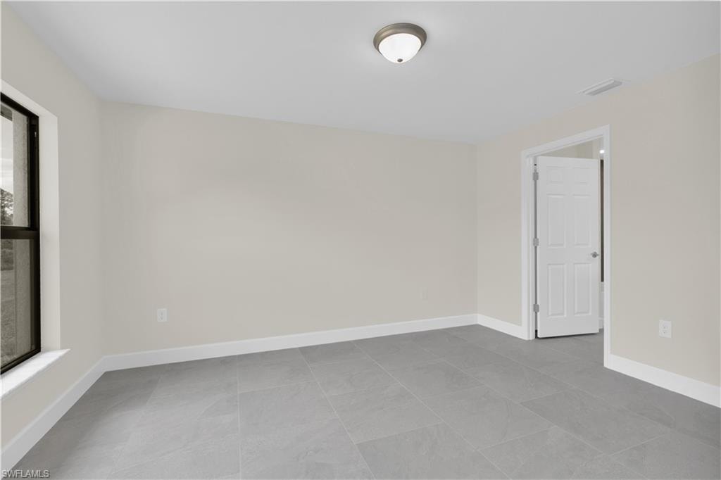 Neutral wall tones with a ceiling-mounted light fixture, tile flooring, and white trim