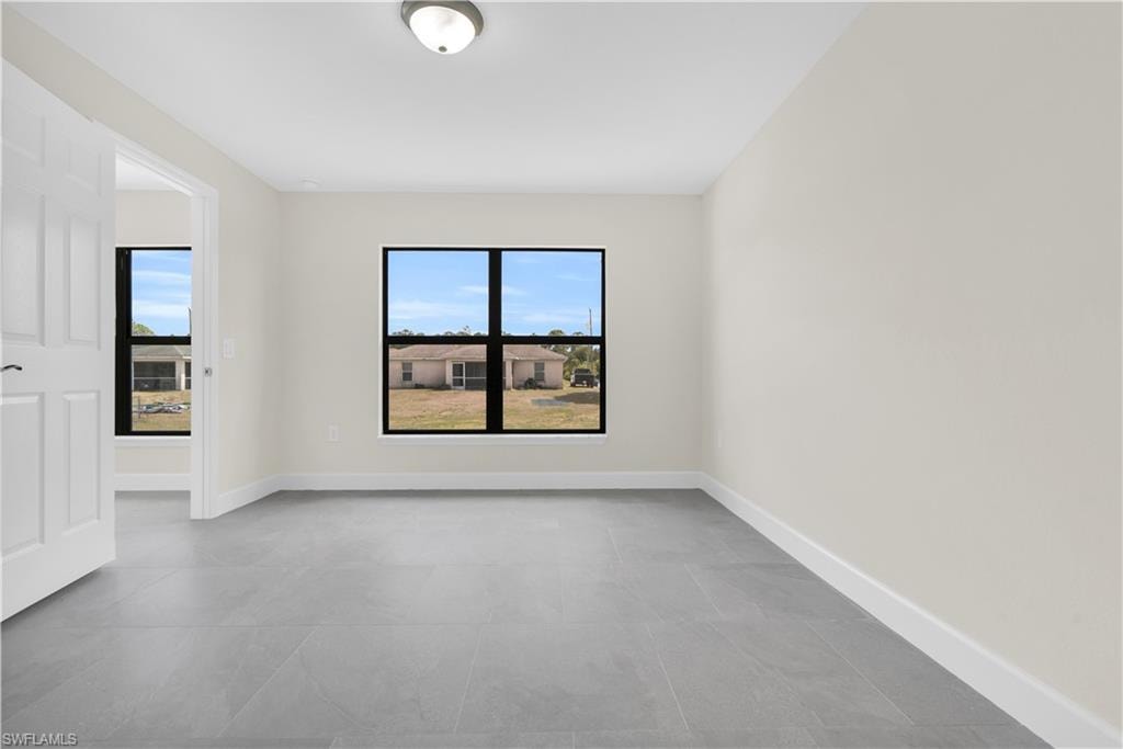 Spacious room featuring light gray tile flooring, crisp white walls, and a large window with a black frame