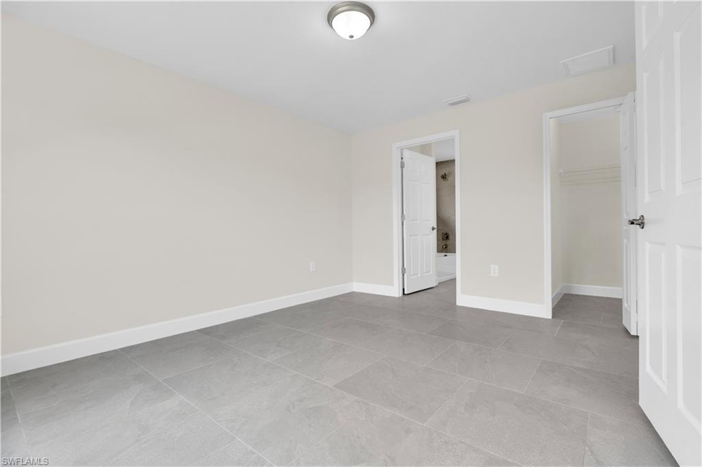 Gray tile flooring, white wall paint, flush mount ceiling light, white paneled door, built-in closet