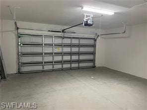 Spacious garage featuring a sectional overhead door, automatic opener, concrete flooring, and fluorescent lighting